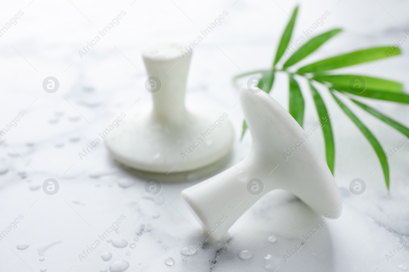 Photo of Wet spa stones and green palm leaf on white marble table, closeup. Space for text