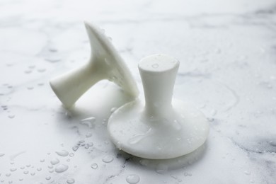 Photo of Wet spa stones on white marble table, closeup