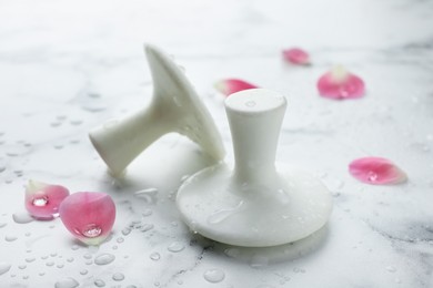 Photo of Wet spa stones and petals on white marble table, closeup