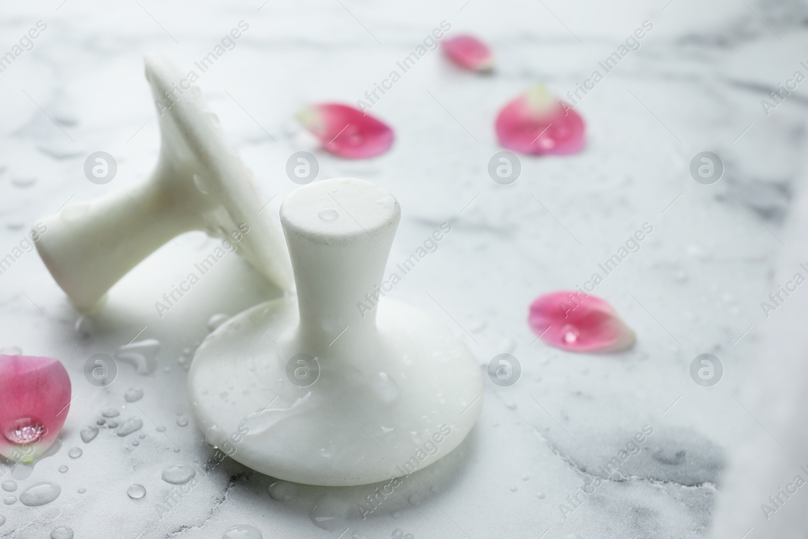 Photo of Wet spa stones and petals on white marble table, closeup. Space for text