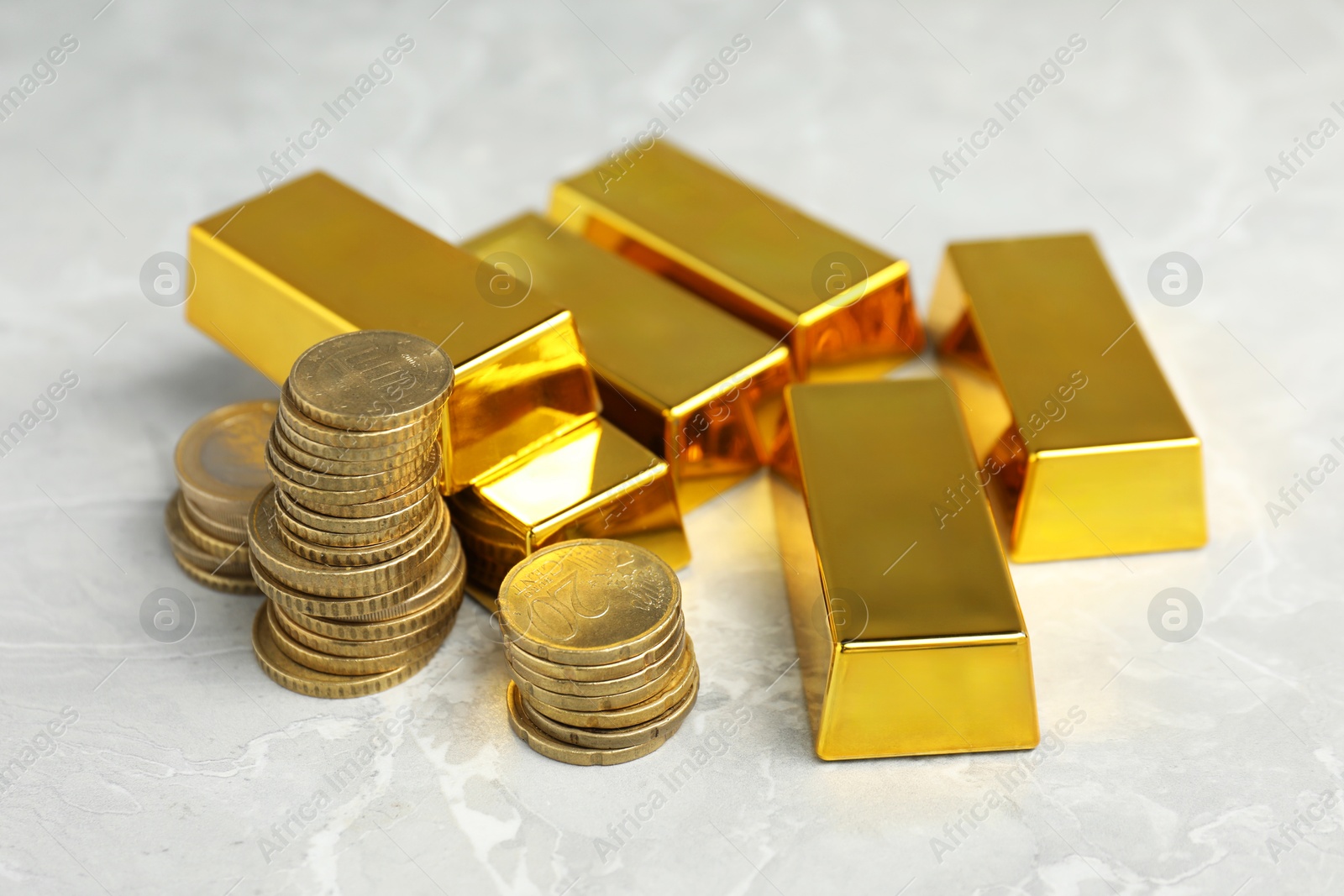 Photo of Gold bars and coins on grey marble table, closeup