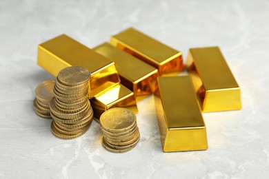 Photo of Gold bars and coins on grey marble table, closeup