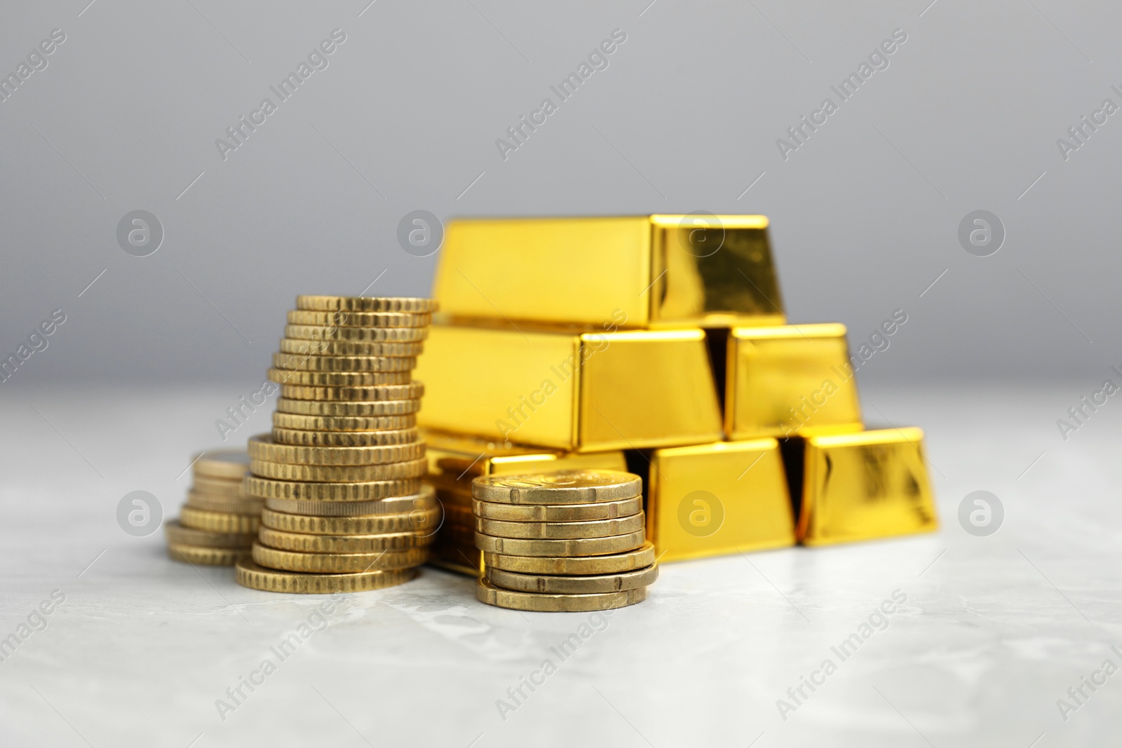 Photo of Gold bars and coins on grey marble table, closeup