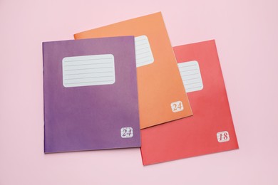 Photo of Colorful copybooks on pink background, flat lay. School stationery