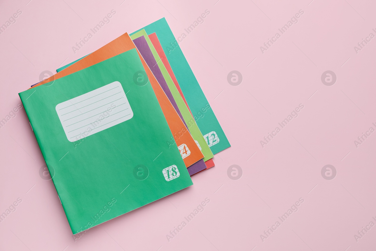 Photo of Colorful copybooks on pink background, flat lay. School stationery