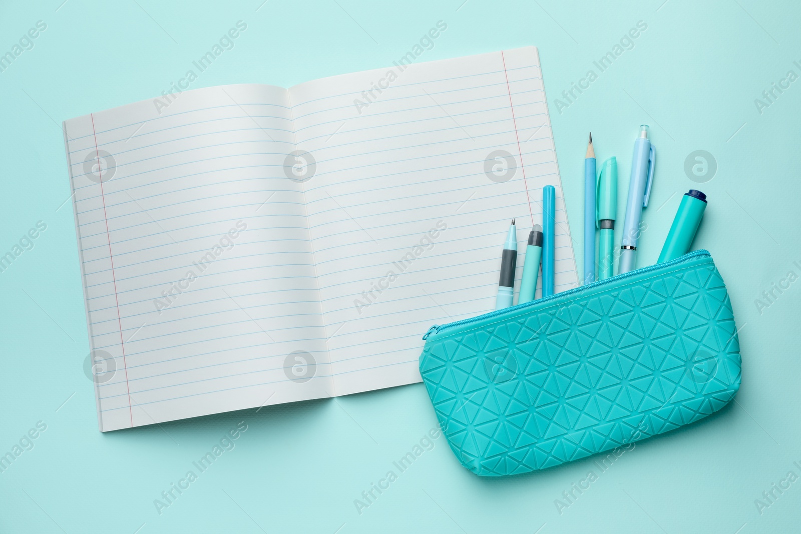 Photo of Open copybook and other school stationery on light blue background, flat lay