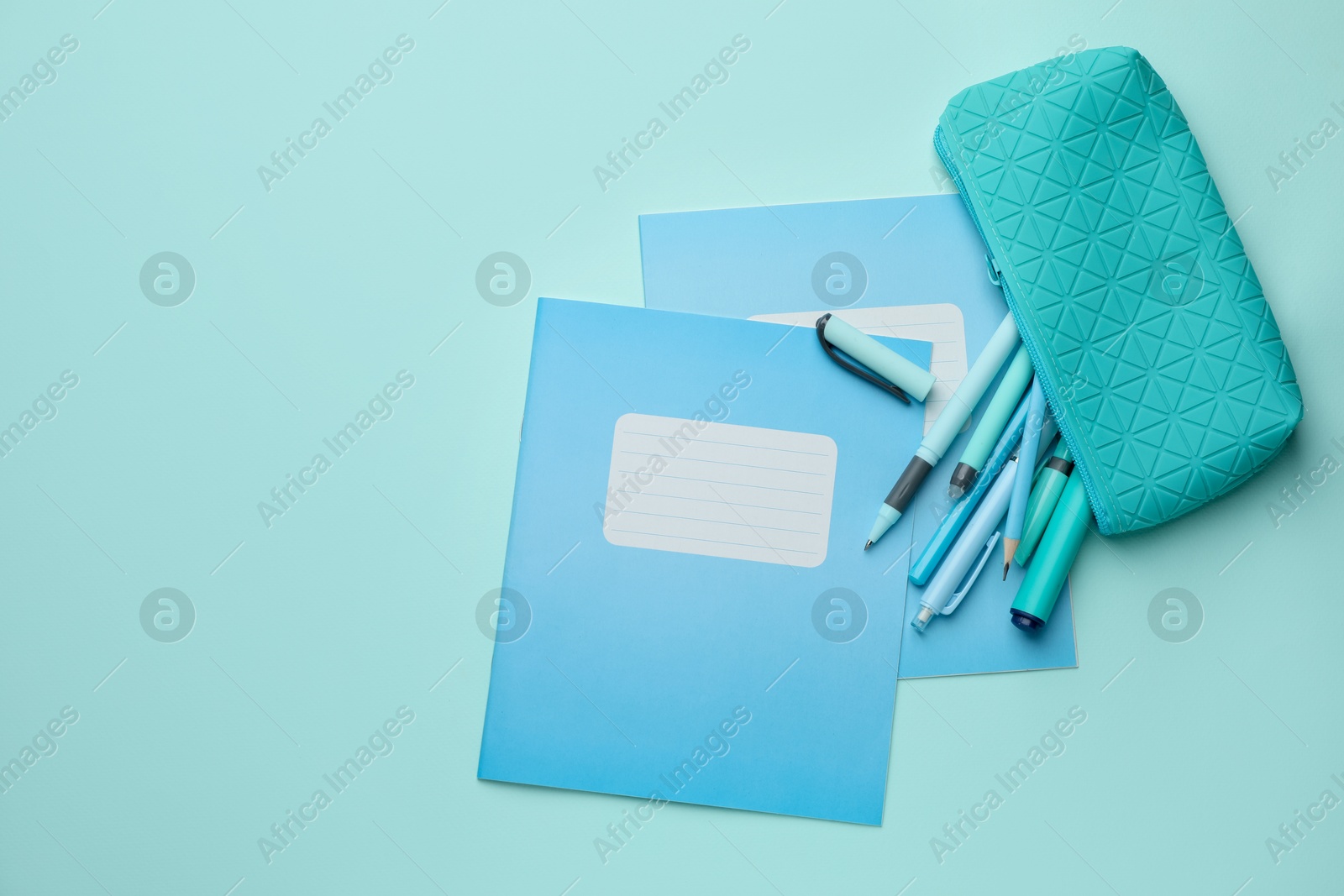 Photo of Copybooks and other school stationery on light blue background, flat lay