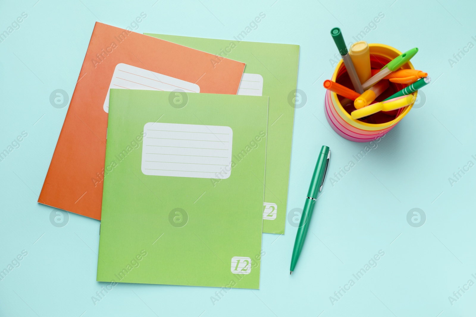 Photo of Copybooks and other school stationery on light blue background, flat lay