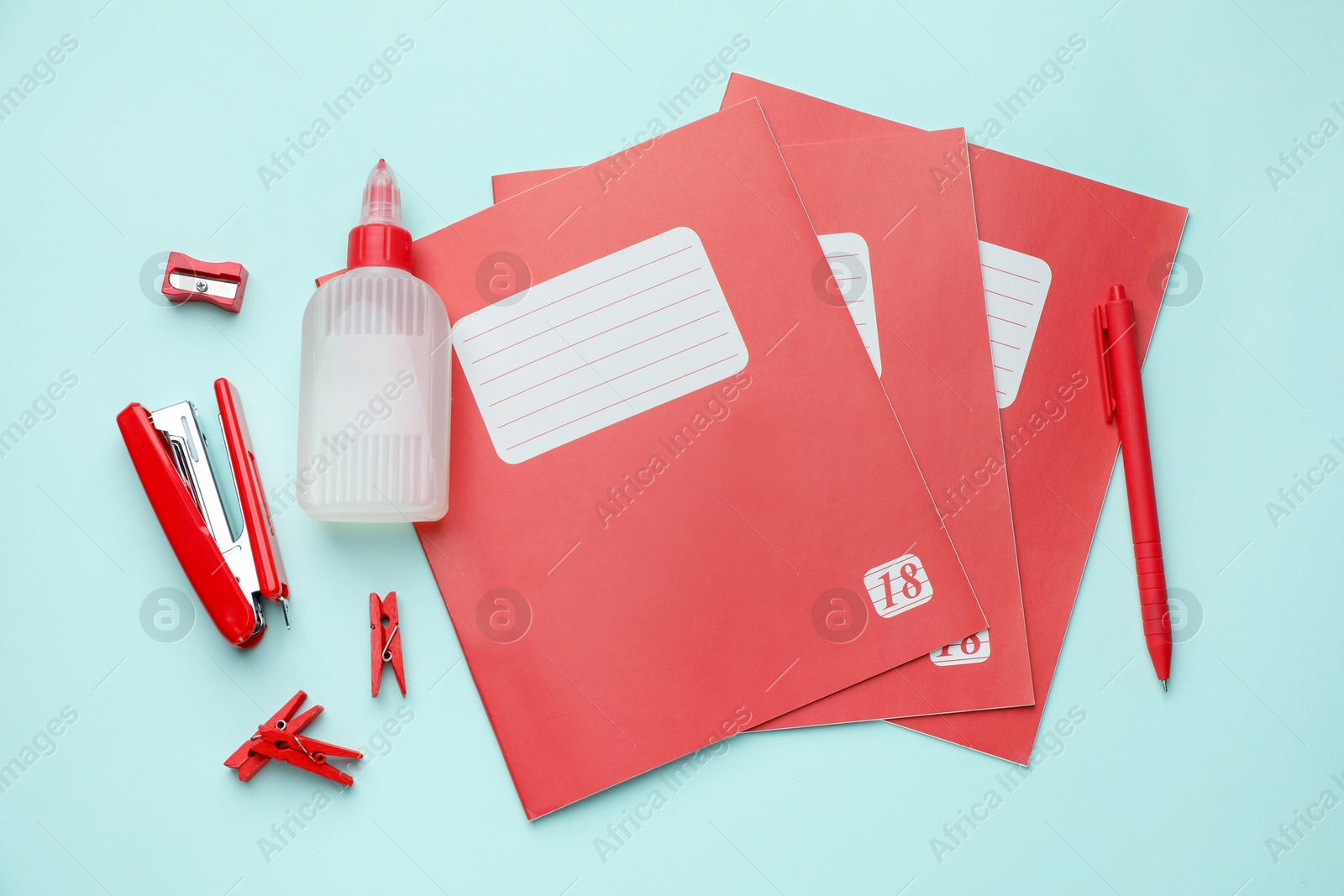 Photo of Copybooks and other school stationery on light blue background, flat lay