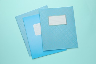 Photo of Colorful copybooks on light blue background, flat lay. School stationery