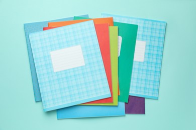 Photo of Colorful copybooks on light blue background, flat lay. School stationery