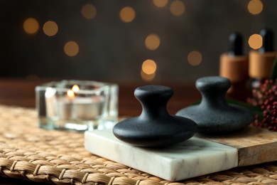 Photo of Spa stones and burning candle on table, closeup