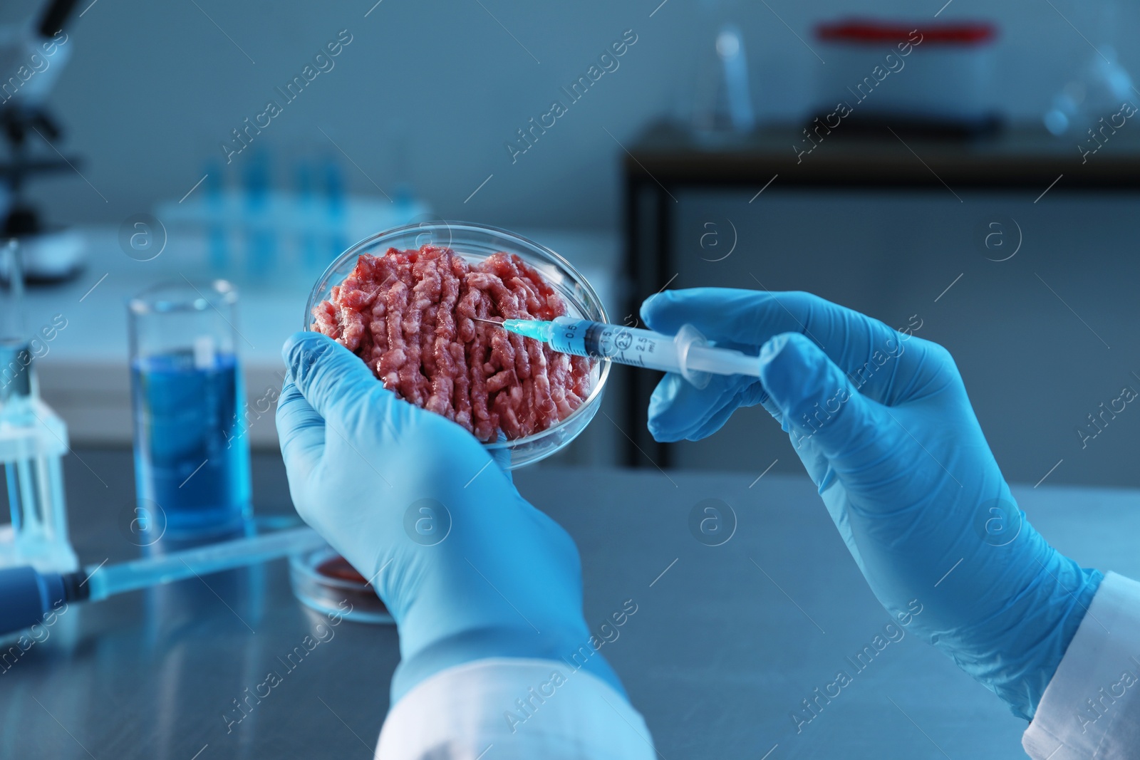 Photo of GMO concept. Scientist injecting something into minced meat in laboratory, closeup