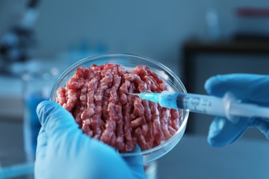 Photo of GMO concept. Scientist injecting something into minced meat in laboratory, closeup