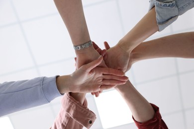 Photo of Unity concept. People holding hands together indoors, bottom view