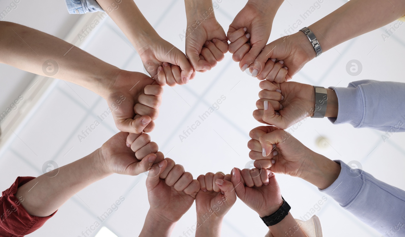 Photo of Unity concept. People holding fists together indoors, bottom view