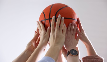 Photo of Unity concept. People holding basketball ball together indoors, closeup