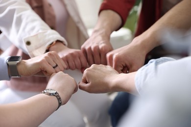 Photo of Unity concept. People holding fists together indoors, closeup