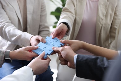 Photo of Unity concept. People putting puzzle pieces together indoors, closeup