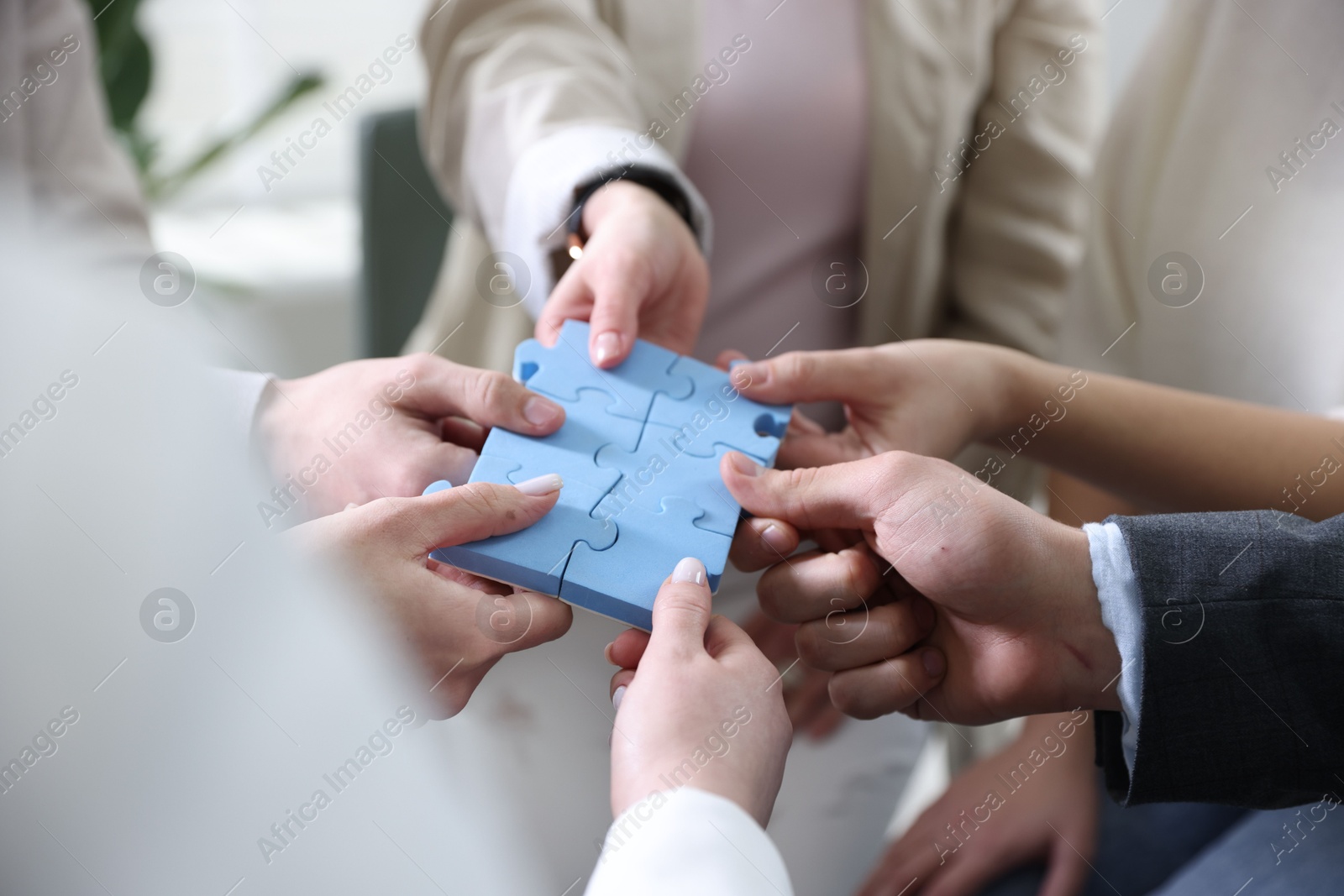 Photo of Unity concept. People putting puzzle pieces together indoors, closeup