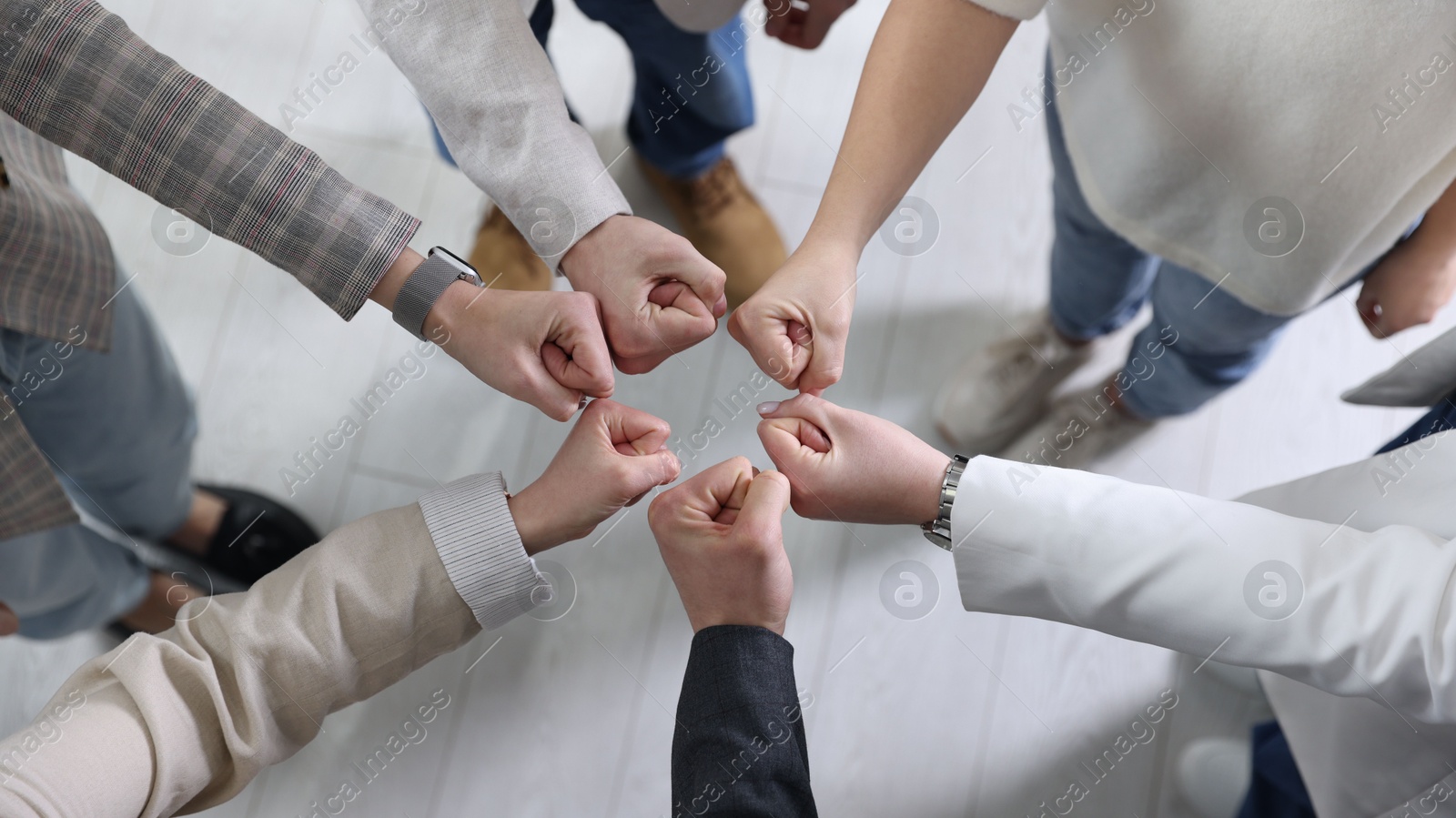 Photo of Unity concept. People holding fists together indoors, top view