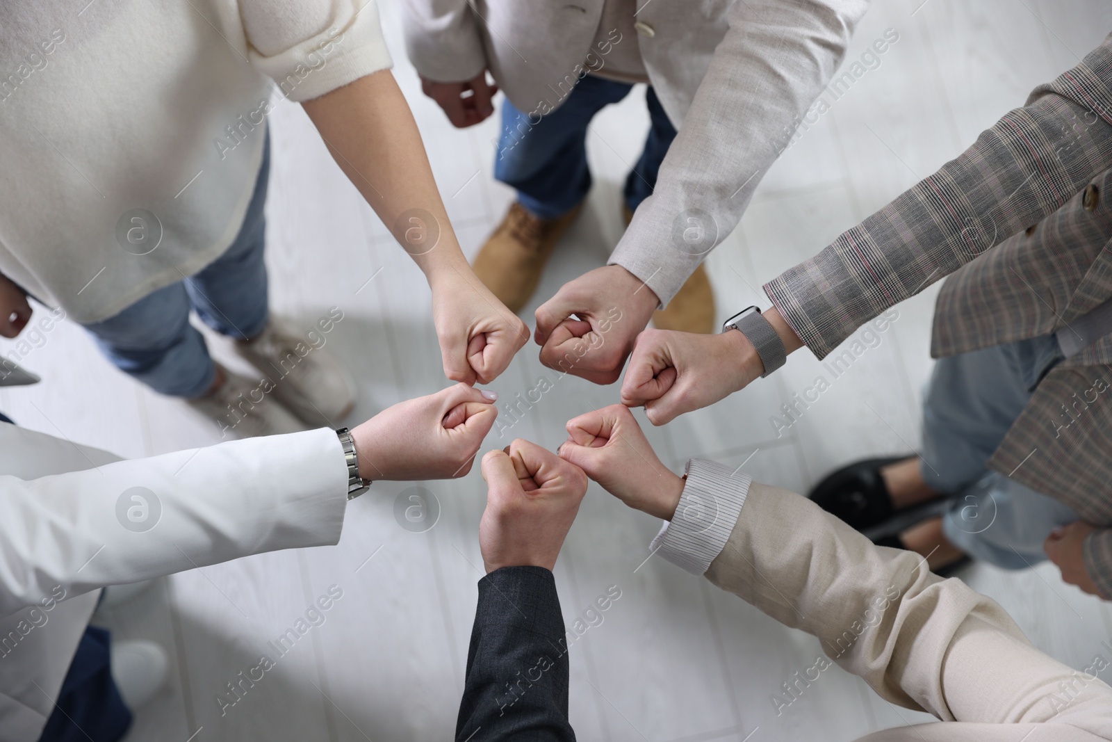 Photo of Unity concept. People holding fists together indoors, top view