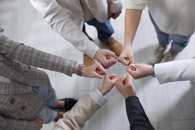 Photo of Unity concept. People holding fists together indoors, top view