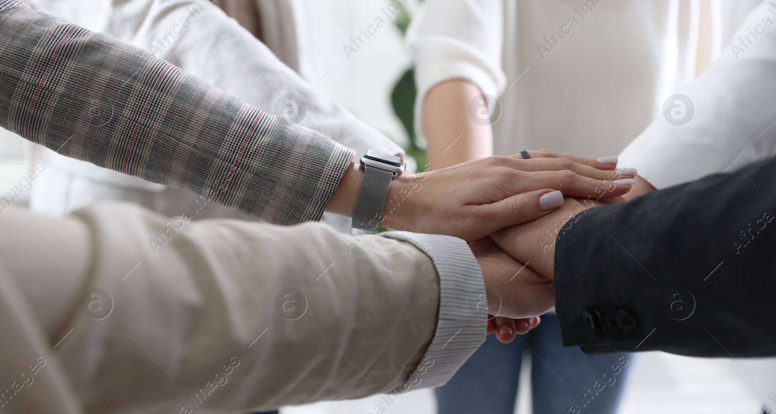 Photo of Unity concept. People holding hands together indoors, closeup