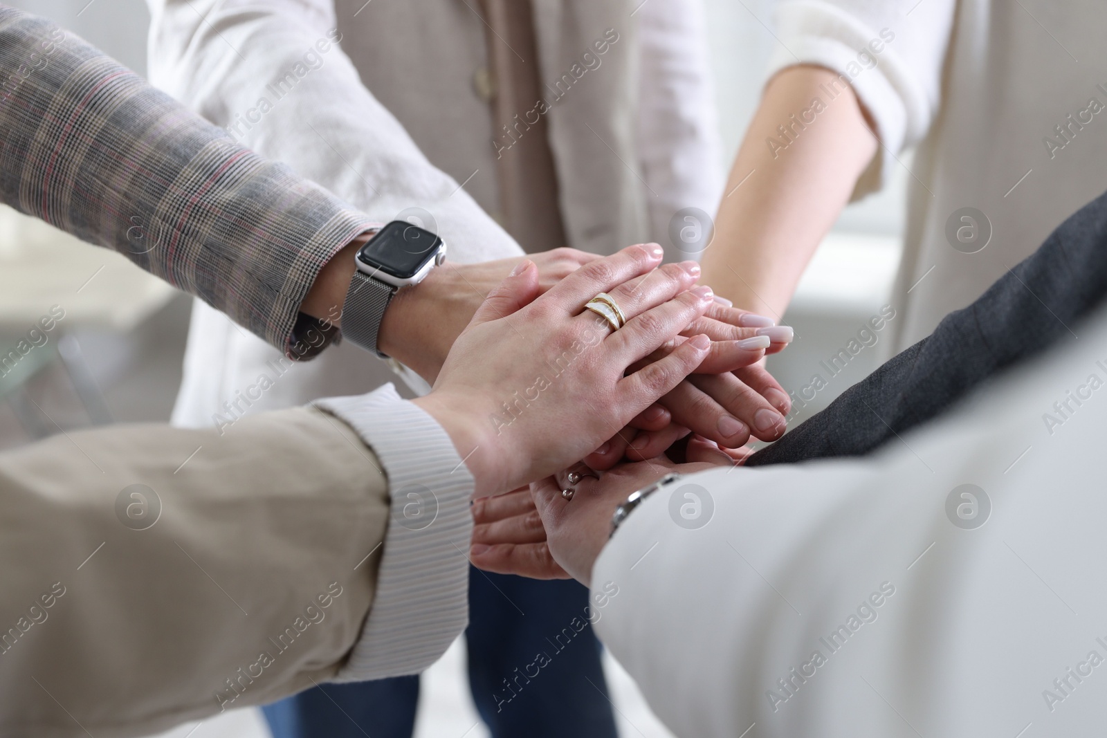 Photo of Unity concept. People holding hands together indoors, closeup