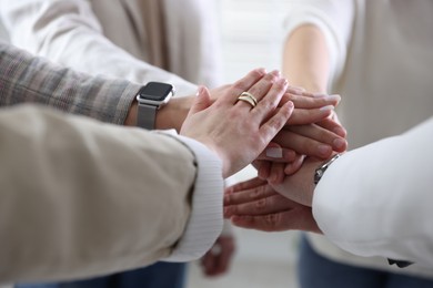 Photo of Unity concept. People holding hands together indoors, closeup