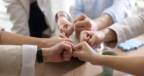 Photo of Unity concept. People holding fists together indoors, closeup