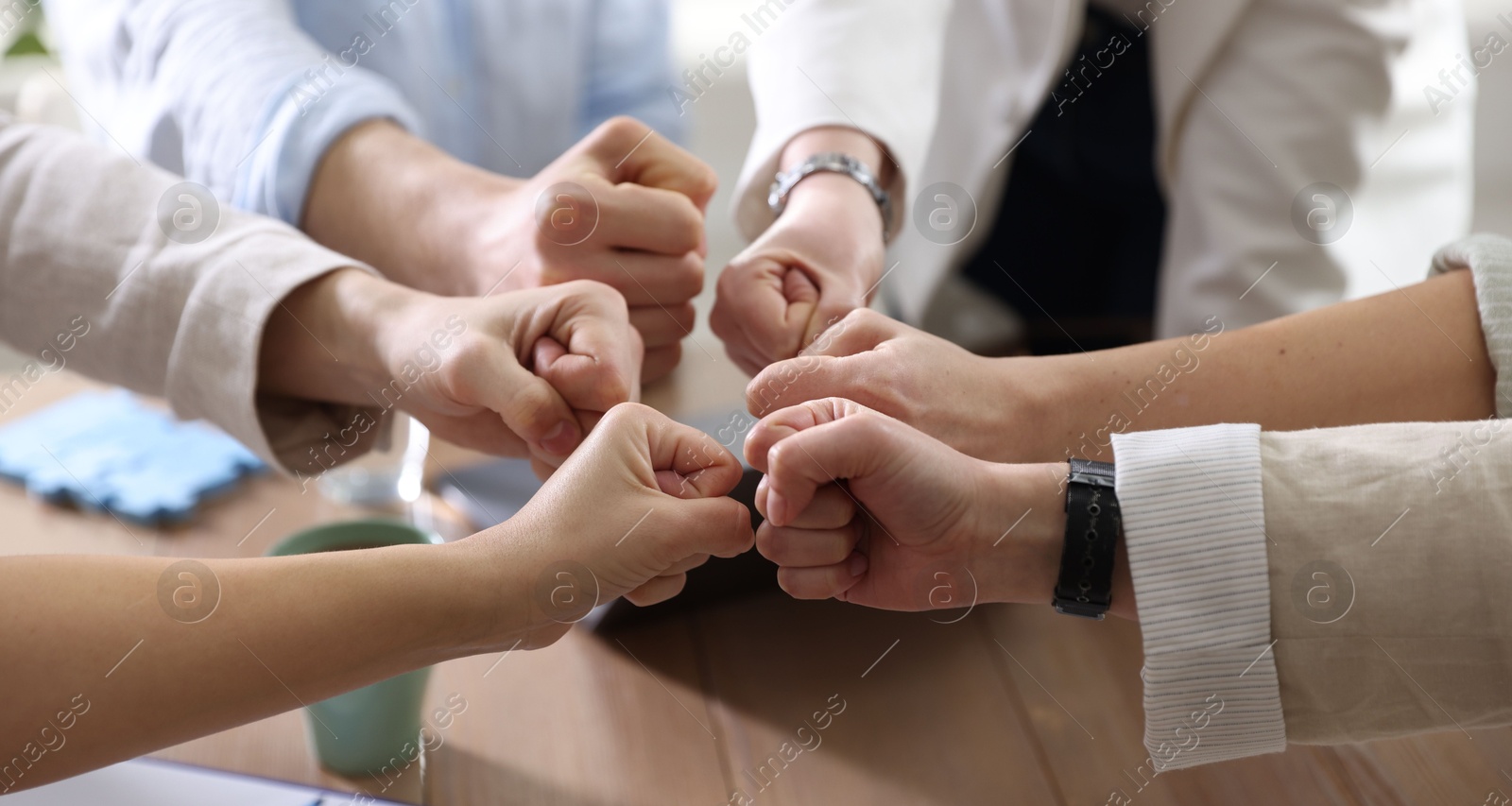 Photo of Unity concept. People holding fists together indoors, closeup