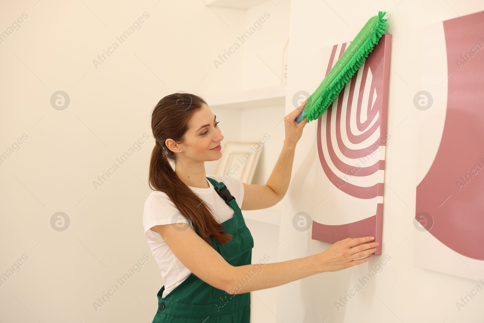 Photo of Professional janitor cleaning dust off picture indoors