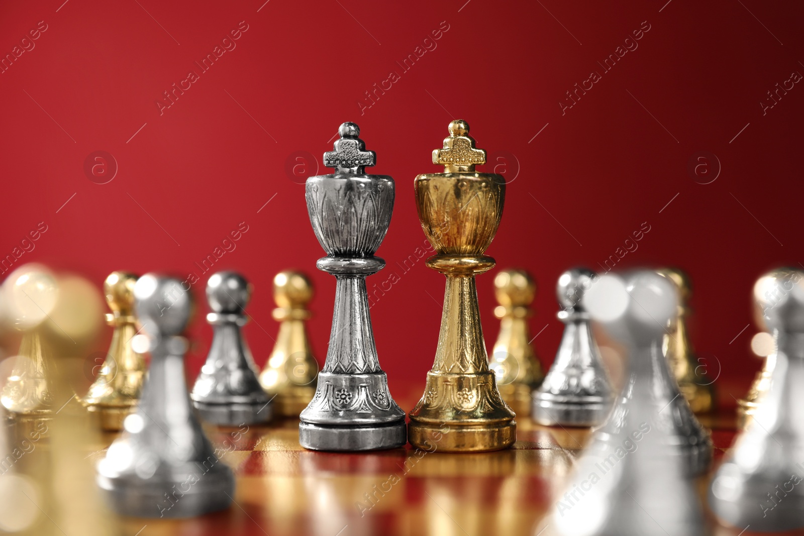 Photo of Golden and silver chess kings among pawns on chessboard. Competition concept