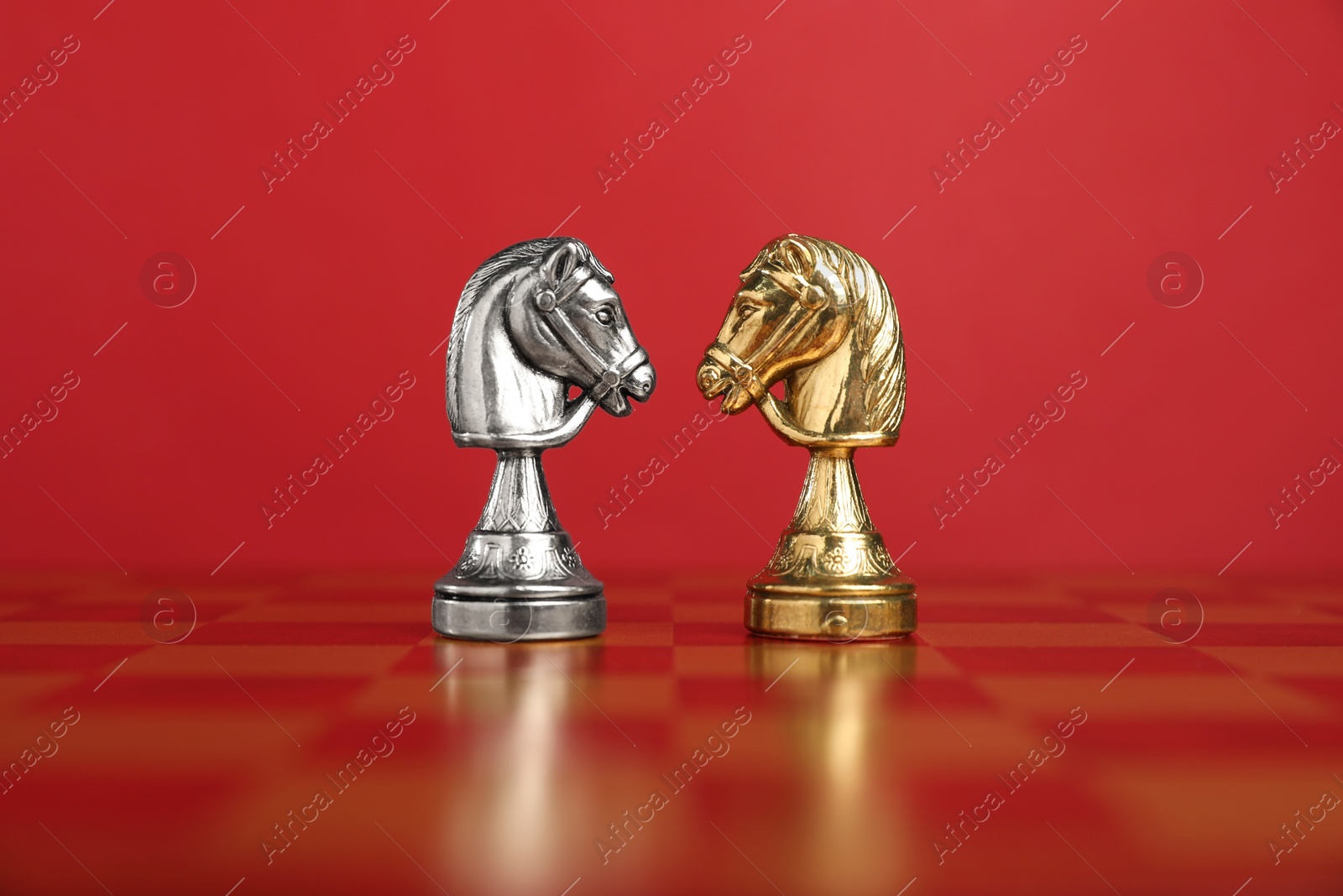 Photo of Golden and silver chess knights in middle of chessboard. Competition concept