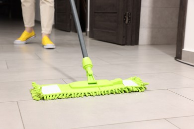 Photo of Woman cleaning floor with microfiber mop indoors, closeup