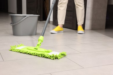 Photo of Woman cleaning floor with microfiber mop indoors, closeup