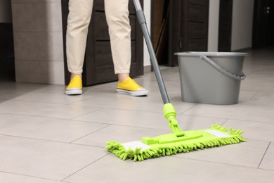 Photo of Woman cleaning floor with microfiber mop indoors, closeup