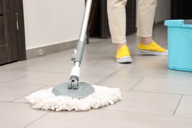 Photo of Woman cleaning floor with string mop indoors, closeup