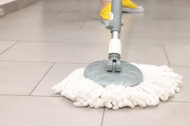 Photo of Woman cleaning floor with string mop indoors, closeup