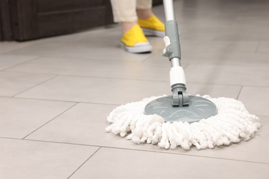 Photo of Woman cleaning floor with string mop indoors, closeup