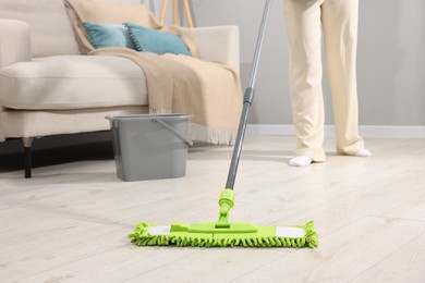 Photo of Woman cleaning floor with microfiber mop indoors, closeup