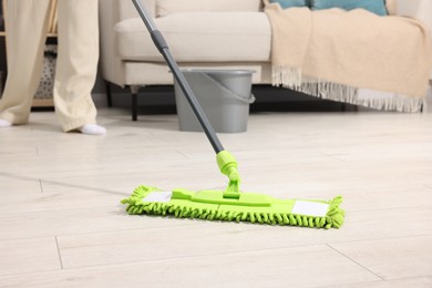 Photo of Woman cleaning floor with microfiber mop indoors, closeup