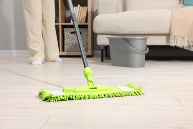 Photo of Woman cleaning floor with microfiber mop indoors, closeup