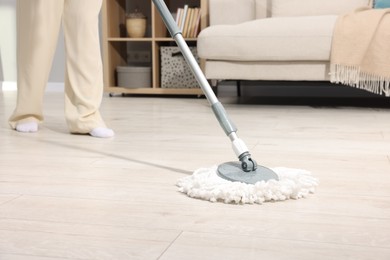 Photo of Woman cleaning floor with string mop indoors, closeup