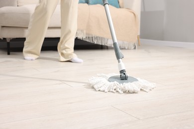 Photo of Woman cleaning floor with string mop indoors, closeup