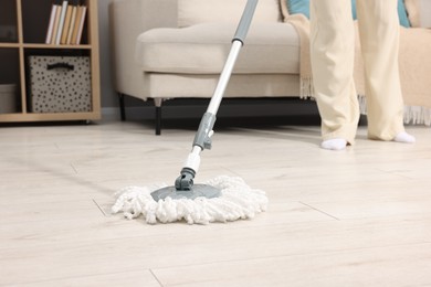 Photo of Woman cleaning floor with string mop indoors, closeup