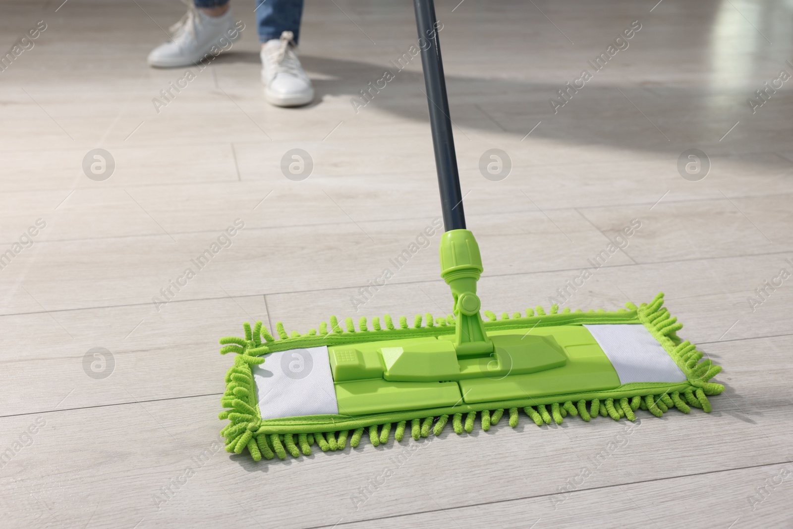 Photo of Woman cleaning floor with microfiber mop indoors, closeup