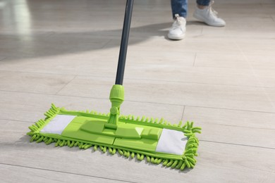 Photo of Woman cleaning floor with microfiber mop indoors, closeup