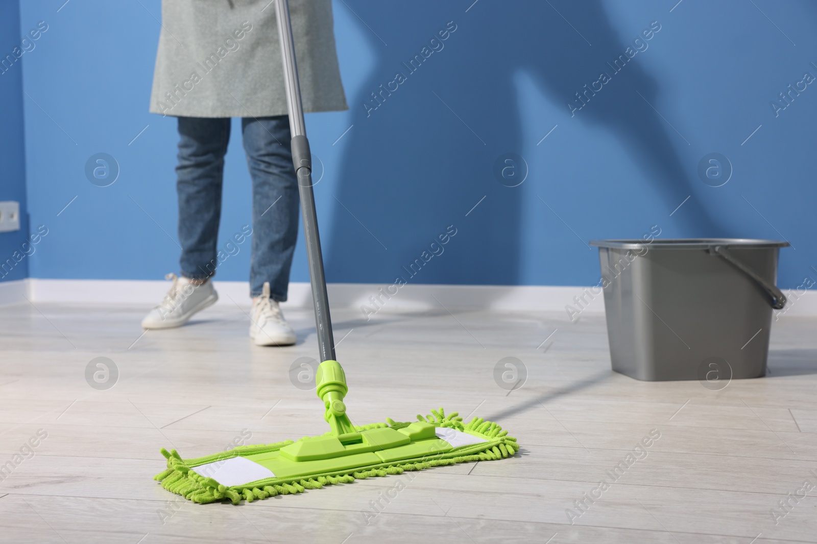 Photo of Woman cleaning floor with microfiber mop indoors, closeup